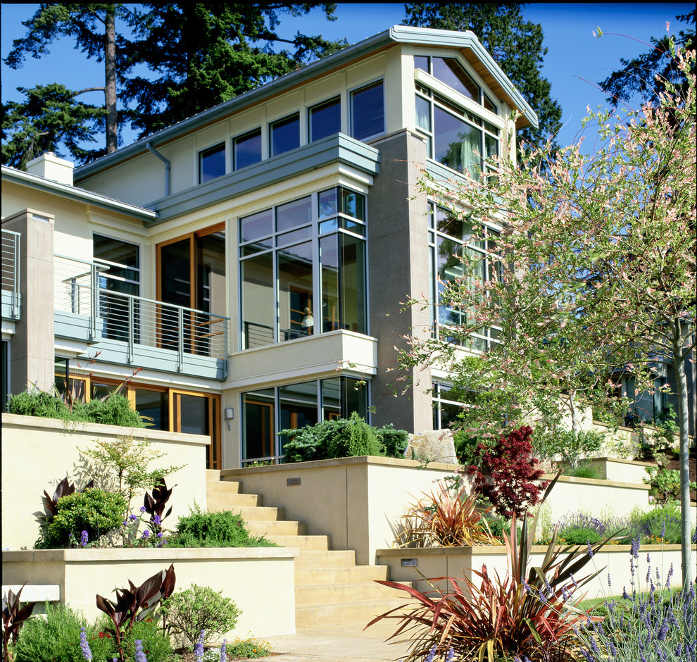 Стильный дизайн: большой, двухэтажный, желтый дом в современном стиле с облицовкой из бетона и двускатной крышей - последний тренд