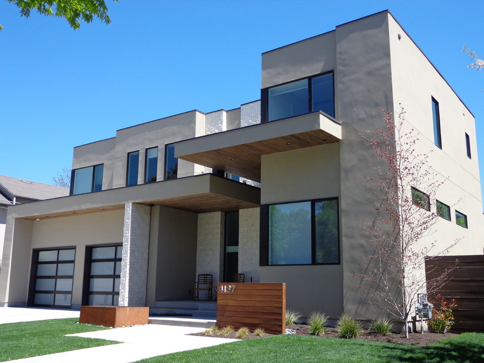 Esempio della facciata di una casa grande beige moderna a due piani con rivestimento in stucco e tetto piano