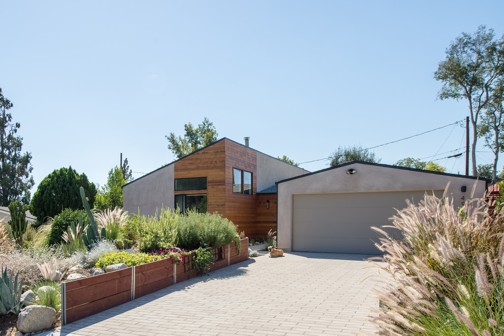 This is an example of a medium sized and gey modern bungalow house exterior in Los Angeles with wood cladding and a pitched roof.