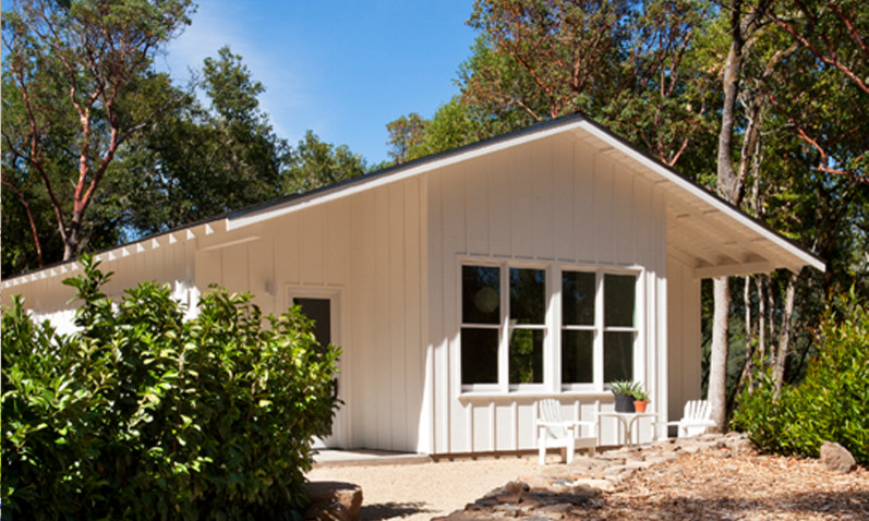 Cette photo montre une petite façade de maison blanche nature en bois de plain-pied avec un toit à deux pans et un toit en shingle.