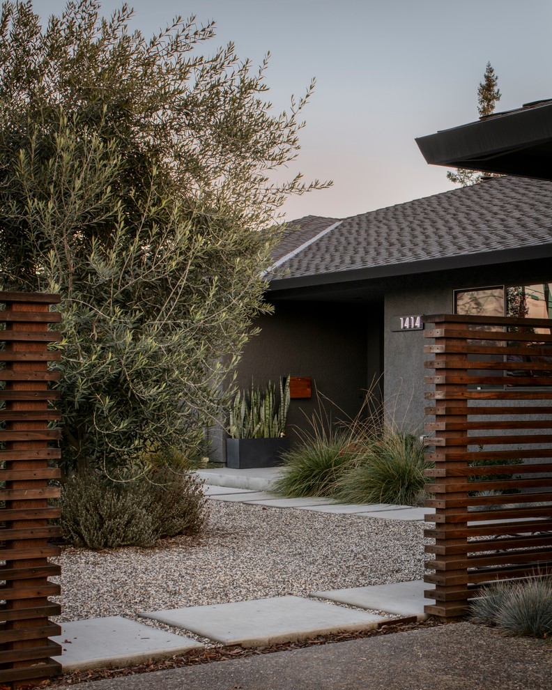 Cette image montre une grande façade de maison grise minimaliste en stuc de plain-pied avec un toit à quatre pans.