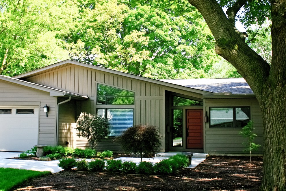 This is an example of a beige contemporary bungalow house exterior in Chicago with vinyl cladding and a hip roof.