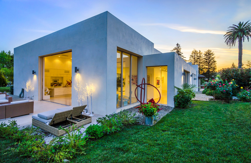 На фото: одноэтажный, серый частный загородный дом в стиле модернизм с облицовкой из цементной штукатурки и плоской крышей с