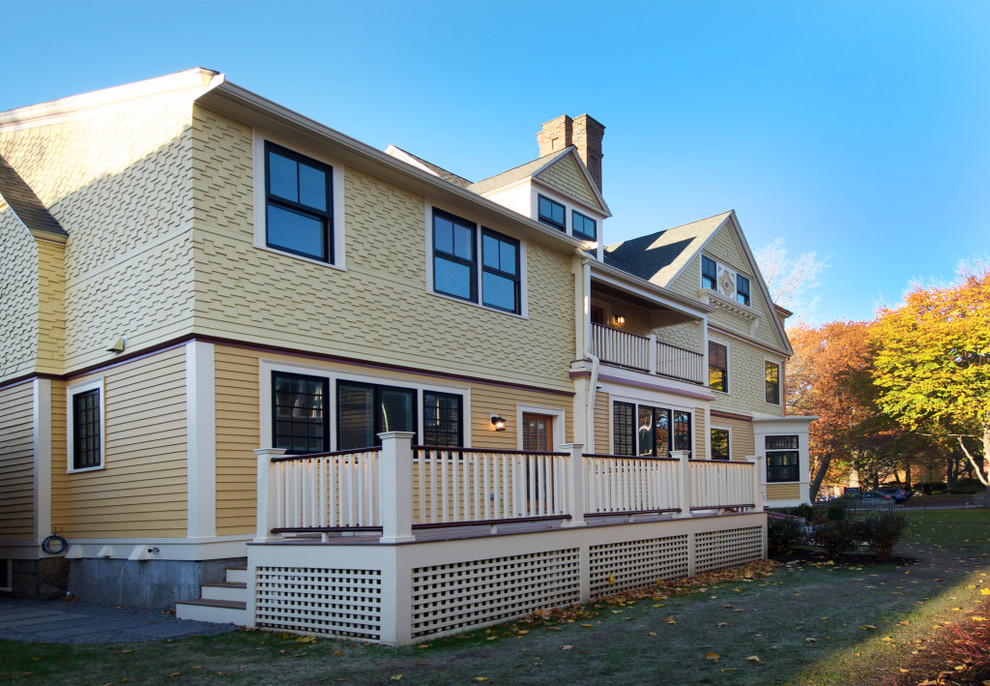 Large ornate yellow three-story wood exterior home photo in Boston with a shingle roof