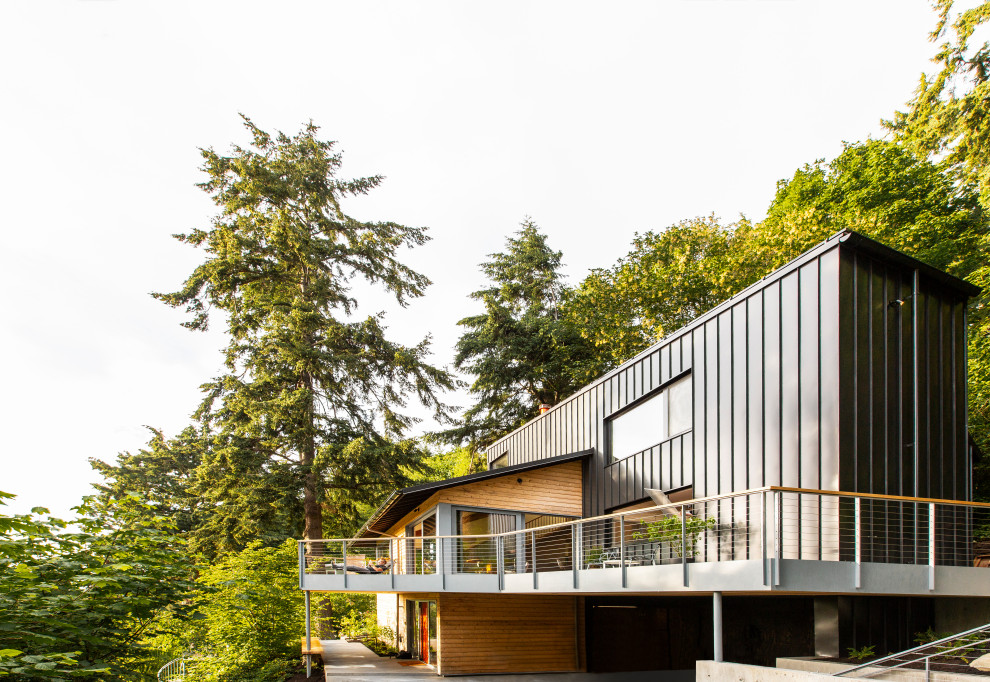This is an example of a large retro detached house in Seattle with three floors, wood cladding, a hip roof and a metal roof.
