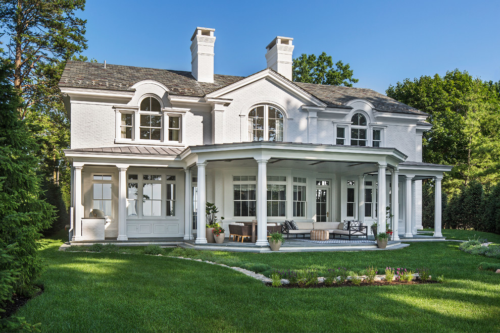 Foto de fachada de casa blanca clásica renovada de tamaño medio de dos plantas con revestimiento de ladrillo, tejado a cuatro aguas y tejado de teja de barro
