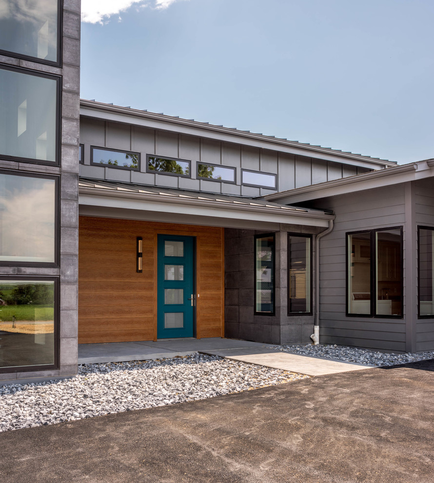 На фото: большой, двухэтажный, серый частный загородный дом в стиле модернизм с облицовкой из ЦСП, двускатной крышей и металлической крышей с