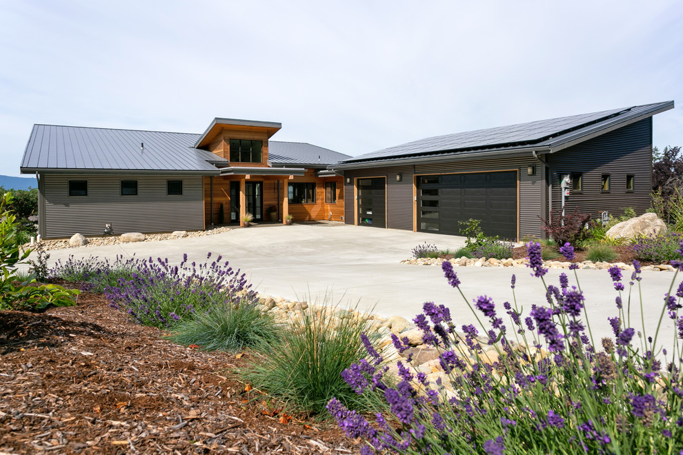 Exemple d'une grande façade de maison grise tendance en bois de plain-pied avec un toit en appentis et un toit en métal.