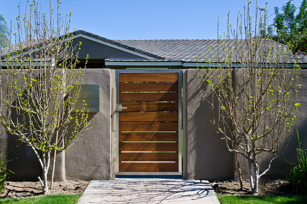 Idée de décoration pour une façade de maison beige design en stuc de taille moyenne et à un étage avec un toit à quatre pans et un toit en shingle.