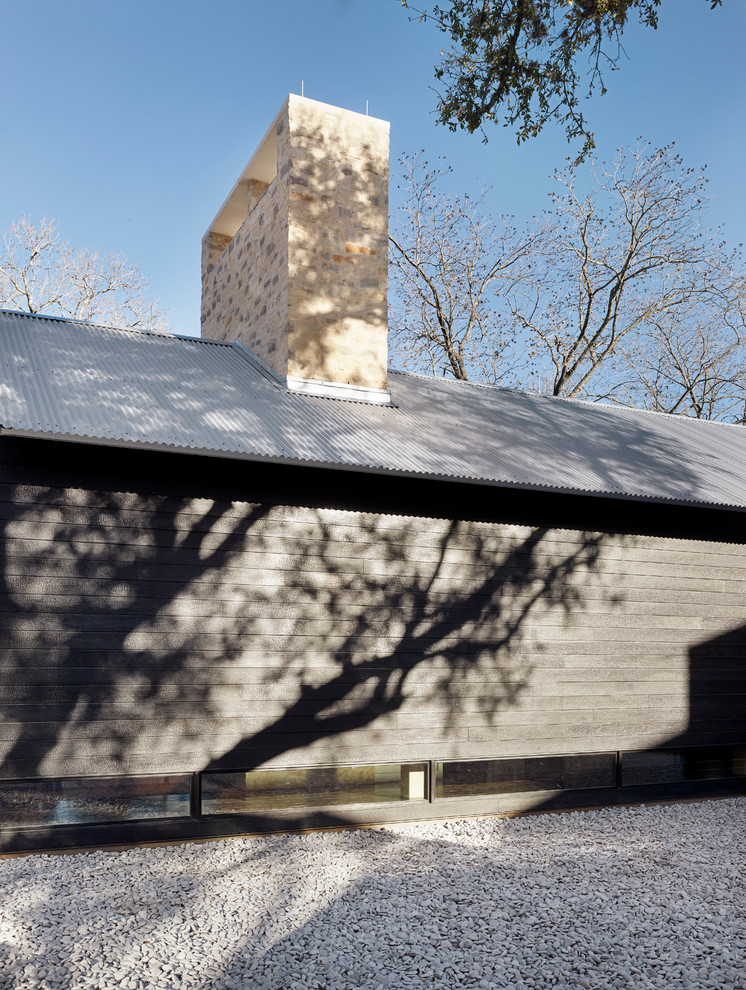 Diseño de fachada de casa negra moderna de dos plantas con revestimiento de madera, tejado de un solo tendido y tejado de metal