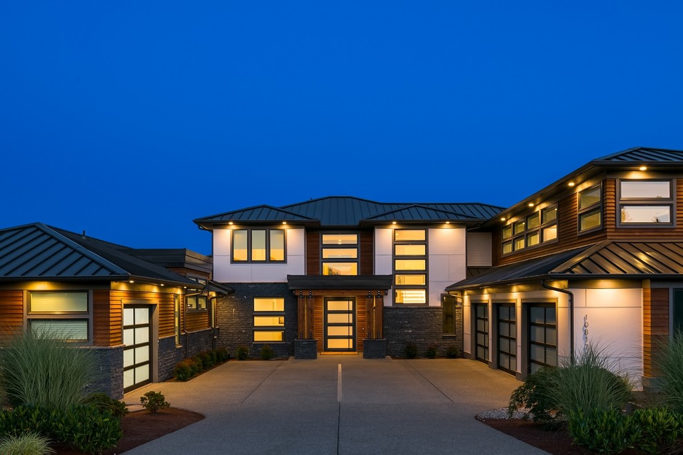 Cette image montre une grande façade de maison grise design à un étage avec un revêtement mixte, un toit à quatre pans et un toit en métal.