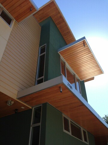 Cette image montre une façade de maison verte minimaliste de taille moyenne et à un étage avec un revêtement en vinyle et un toit plat.