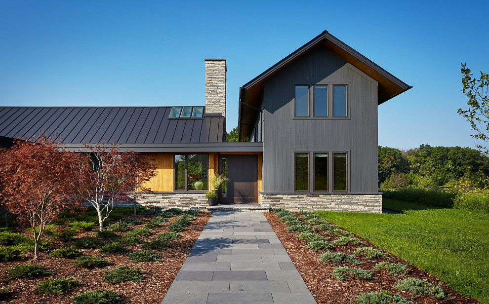 Imagen de fachada de casa negra minimalista grande de dos plantas con tejado a dos aguas