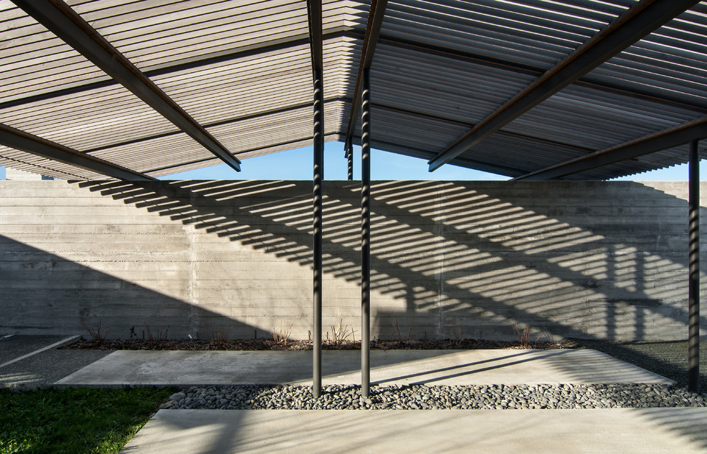 Foto della facciata di una casa grande grigia contemporanea a un piano con rivestimento in cemento e tetto a capanna