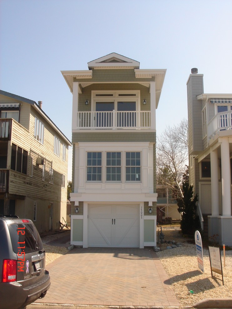 Cette image montre une petite façade de maison verte marine à un étage avec un revêtement en vinyle.