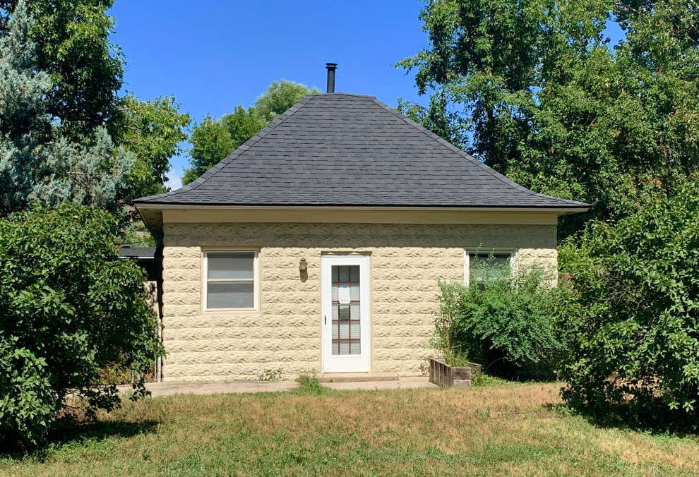 Cette image montre une façade de maison jaune traditionnelle en brique de taille moyenne et de plain-pied avec un toit à quatre pans et un toit en shingle.