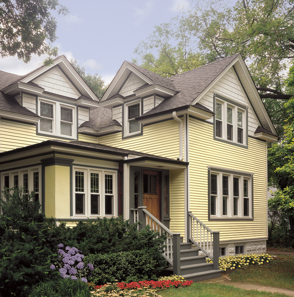 Foto della facciata di una casa gialla classica a due piani di medie dimensioni con rivestimento in vinile