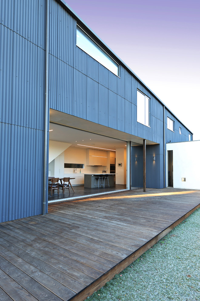 Réalisation d'une grande façade de maison métallique et bleue urbaine à un étage avec un toit en shingle.