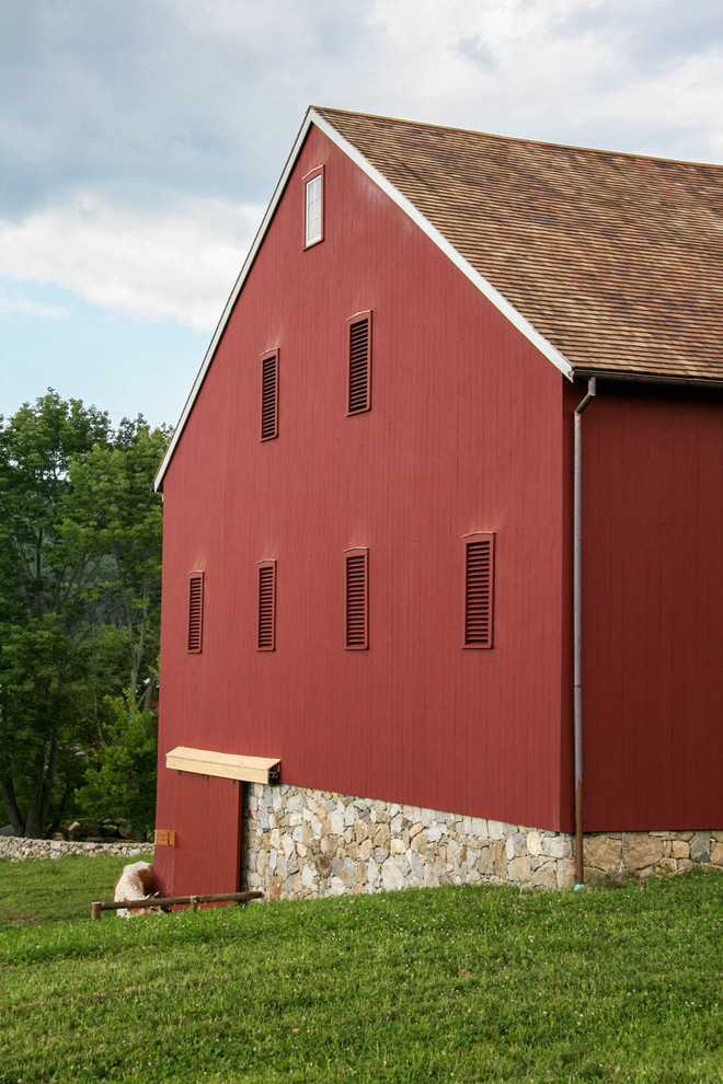 Immagine della facciata di una casa grande rossa country a tre piani con rivestimento in legno e tetto a capanna