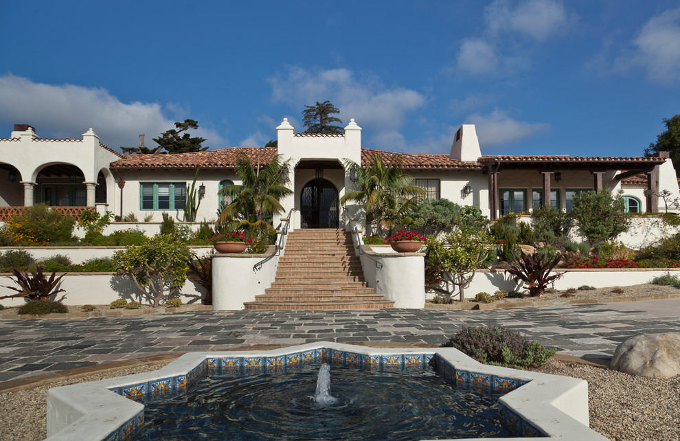 Large mediterranean white one-story stucco house exterior idea in Santa Barbara with a hip roof and a tile roof