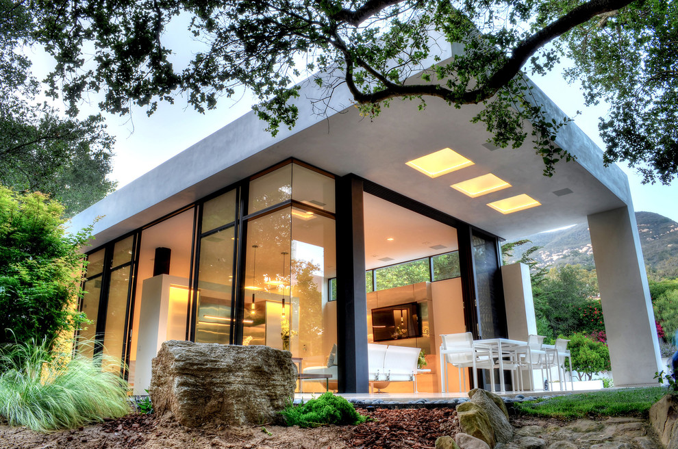 Cette image montre une grande façade de maison blanche minimaliste en stuc de plain-pied.