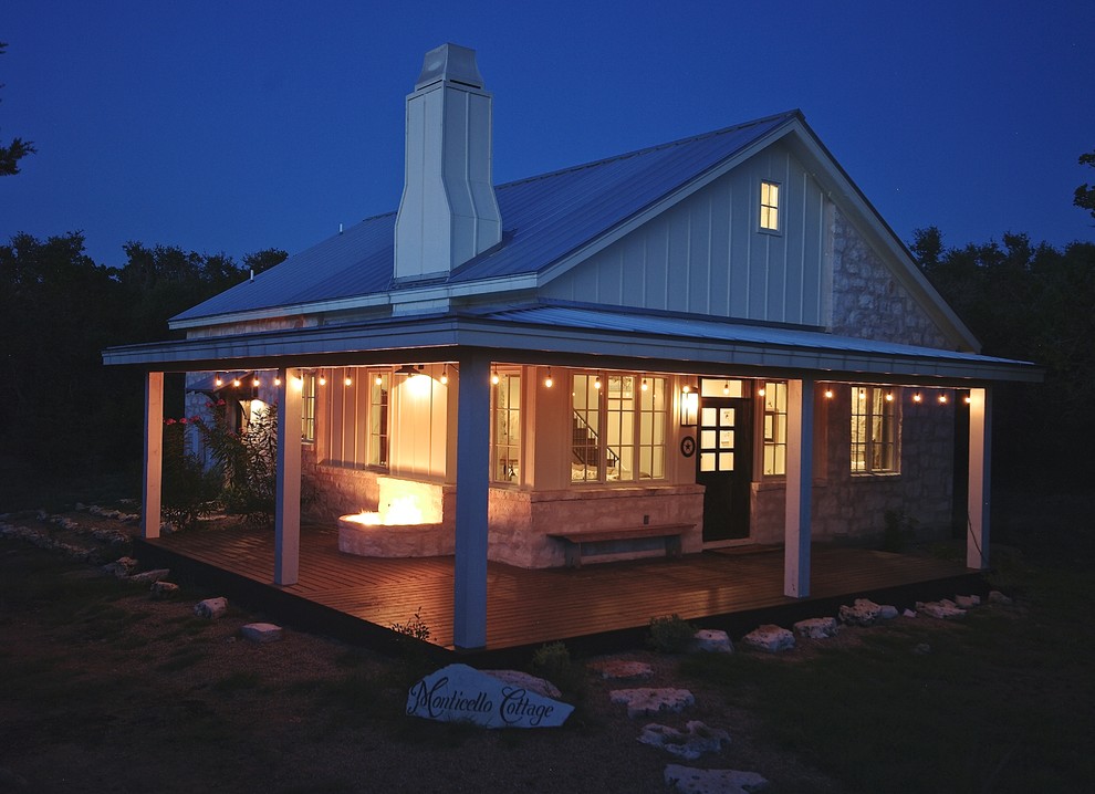 Immagine della facciata di una casa piccola bianca country a due piani con rivestimento in pietra e tetto a capanna