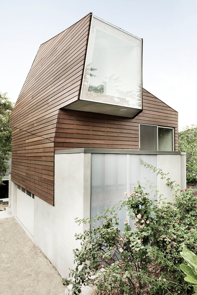 Cette image montre une petite façade de maison grise design en bois à un étage.