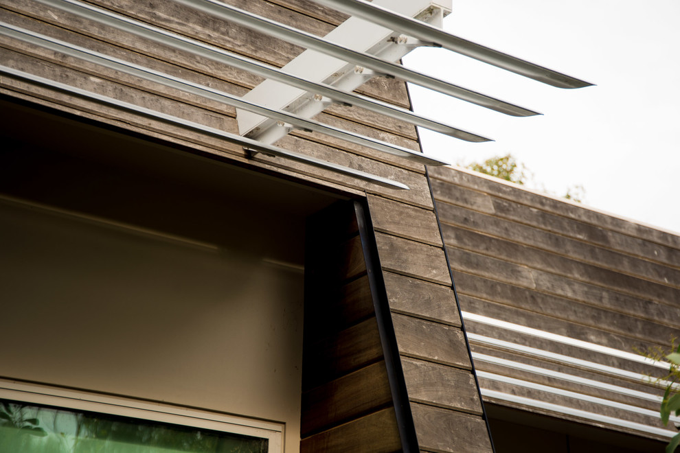 Réalisation d'une façade de maison grise design en bois de taille moyenne et de plain-pied.