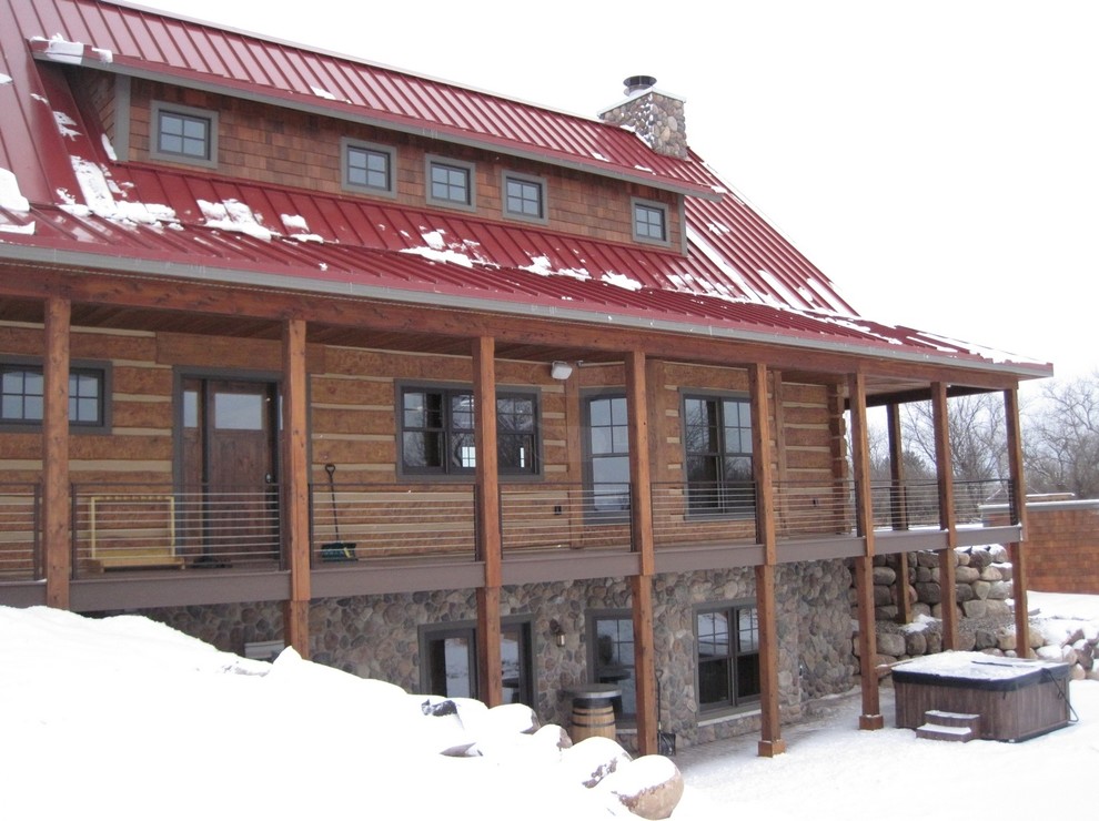 На фото: двухэтажный, коричневый дом среднего размера в стиле рустика с двускатной крышей для охотников с