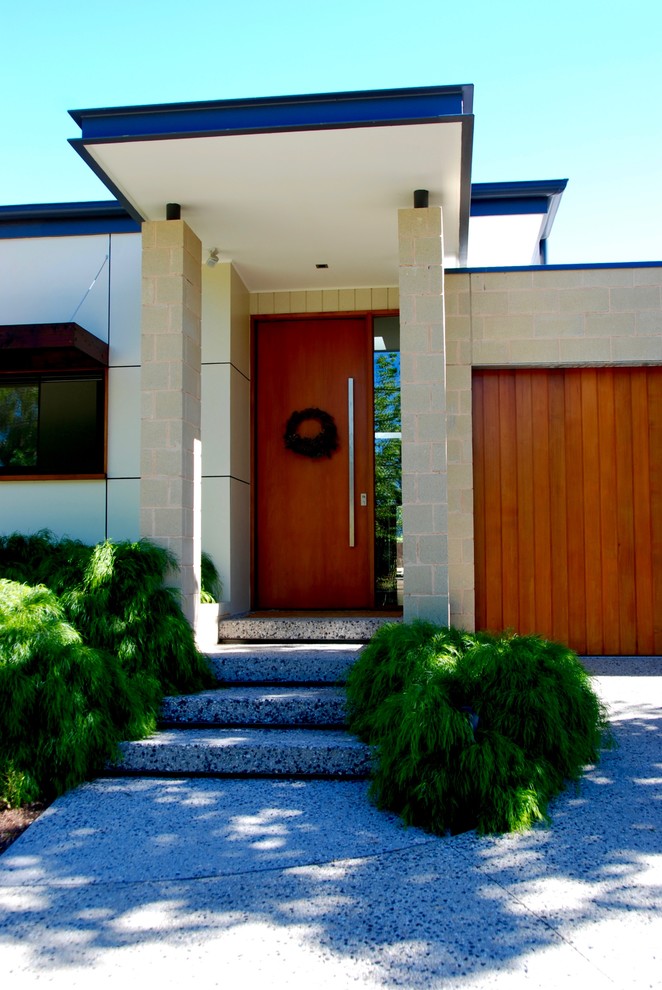 Modelo de fachada de casa beige contemporánea de dos plantas con revestimientos combinados y tejado plano