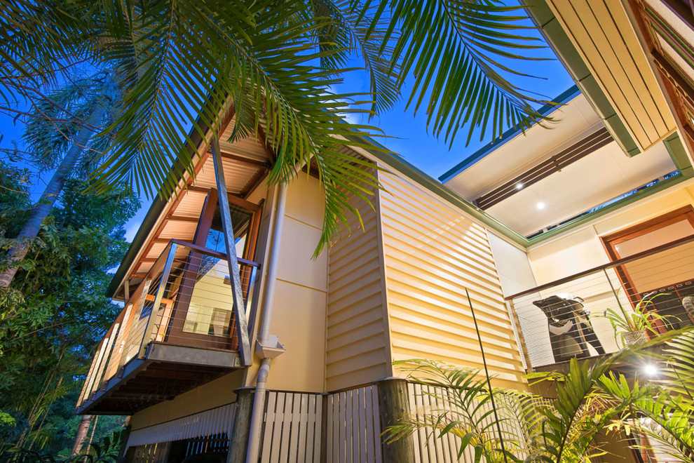 Ejemplo de fachada de casa multicolor tropical grande de dos plantas con tejado a cuatro aguas y tejado de metal