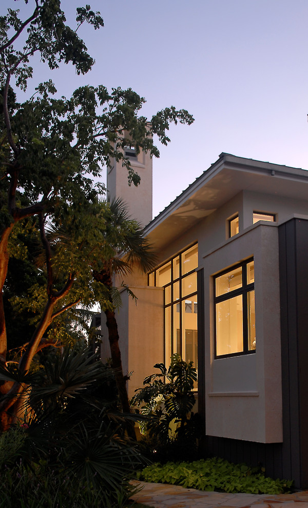 Expansive and white modern bungalow house exterior in Miami with mixed cladding and a hip roof.