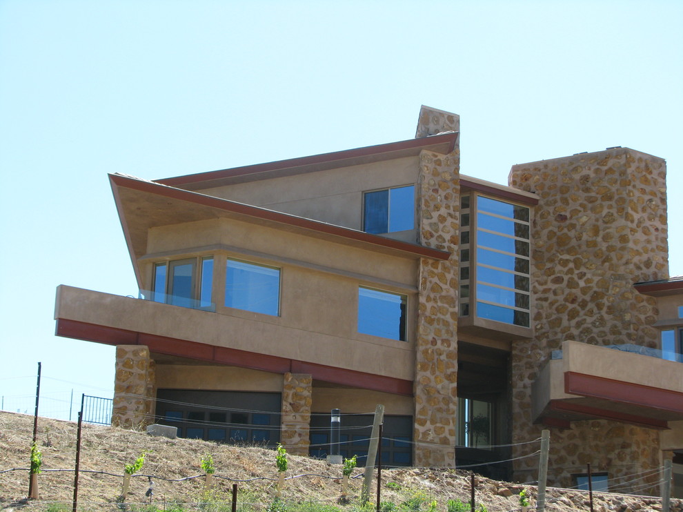 Exempel på ett stort modernt beige hus, med tre eller fler plan, stuckatur och valmat tak