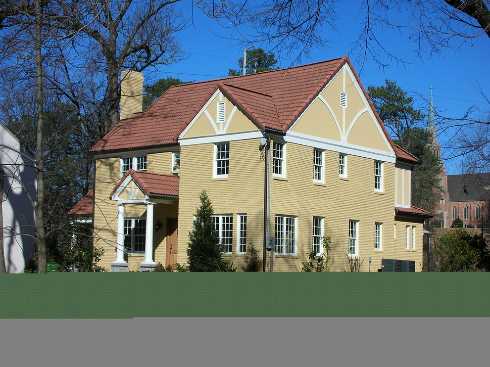 Cette image montre une façade de maison jaune traditionnelle en brique de taille moyenne et à un étage avec un toit à deux pans.