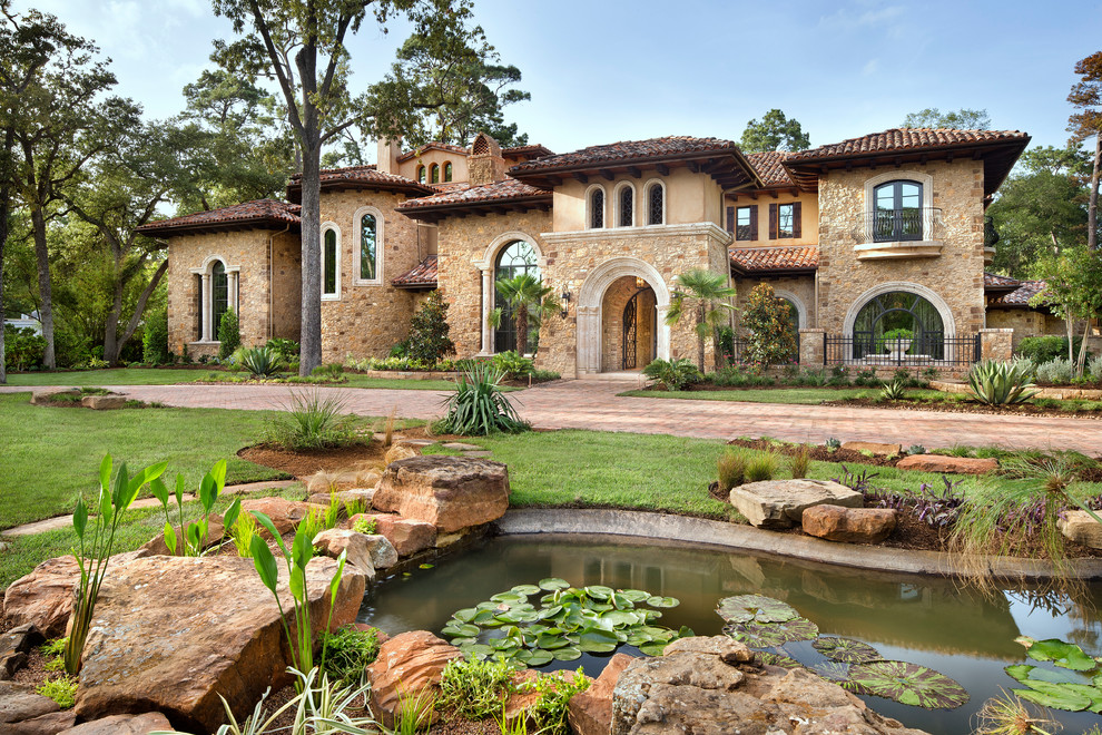 Huge mediterranean beige split-level mixed siding house exterior idea in Houston with a hip roof and a tile roof