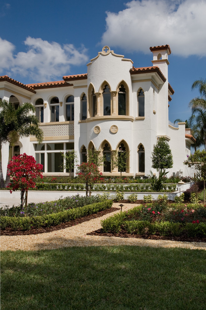 На фото: большой, двухэтажный, белый дом в средиземноморском стиле с облицовкой из цементной штукатурки и вальмовой крышей с