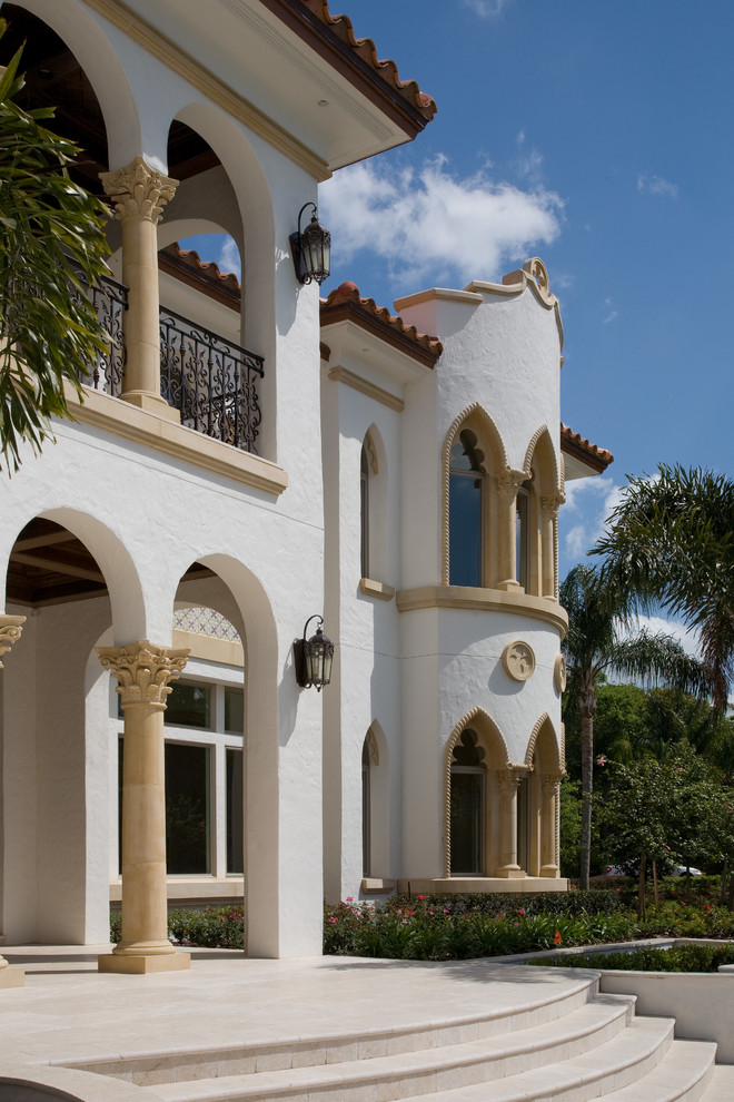 Пример оригинального дизайна: большой, двухэтажный, белый дом в средиземноморском стиле с облицовкой из цементной штукатурки и вальмовой крышей