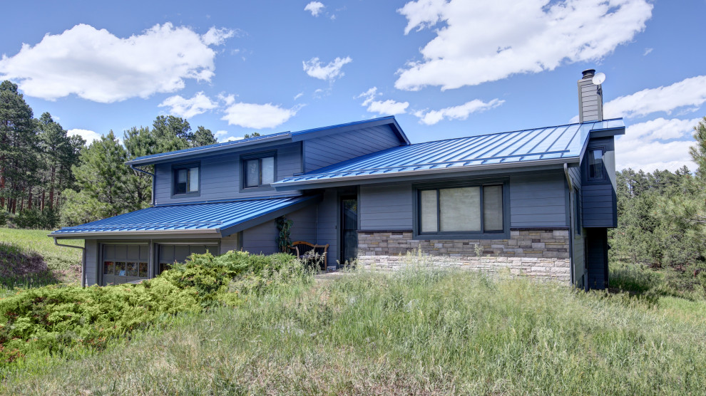 Ispirazione per la villa blu rustica a due piani di medie dimensioni con rivestimento con lastre in cemento, tetto a capanna e copertura in metallo o lamiera