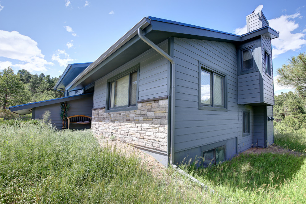 На фото: двухэтажный, синий частный загородный дом среднего размера в стиле рустика с облицовкой из ЦСП, двускатной крышей и металлической крышей