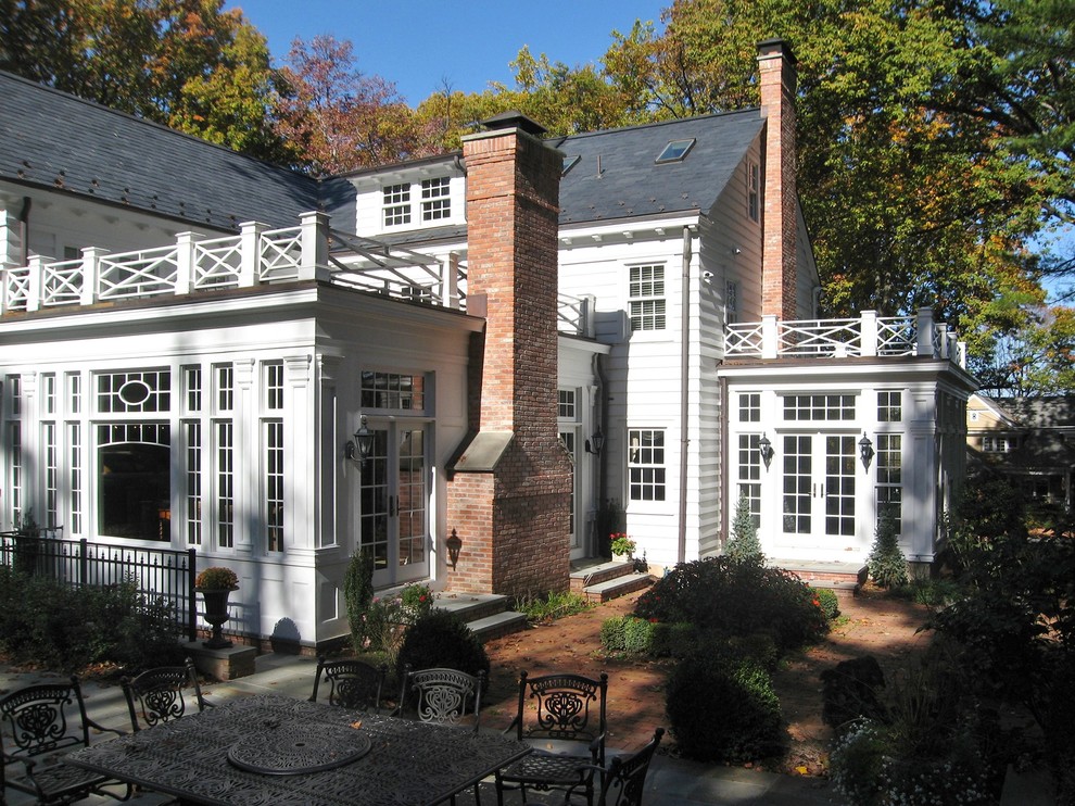 Immagine della facciata di una casa grande bianca classica a due piani con rivestimento in legno e tetto a capanna