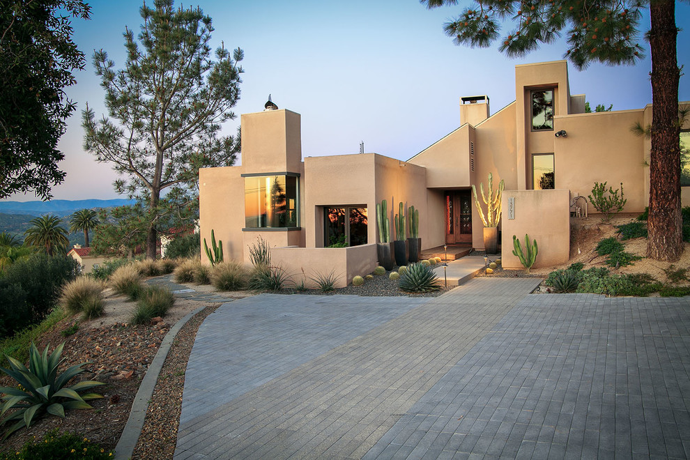 Aménagement d'une grande façade de maison beige moderne en adobe de plain-pied avec un toit en appentis et un toit en shingle.