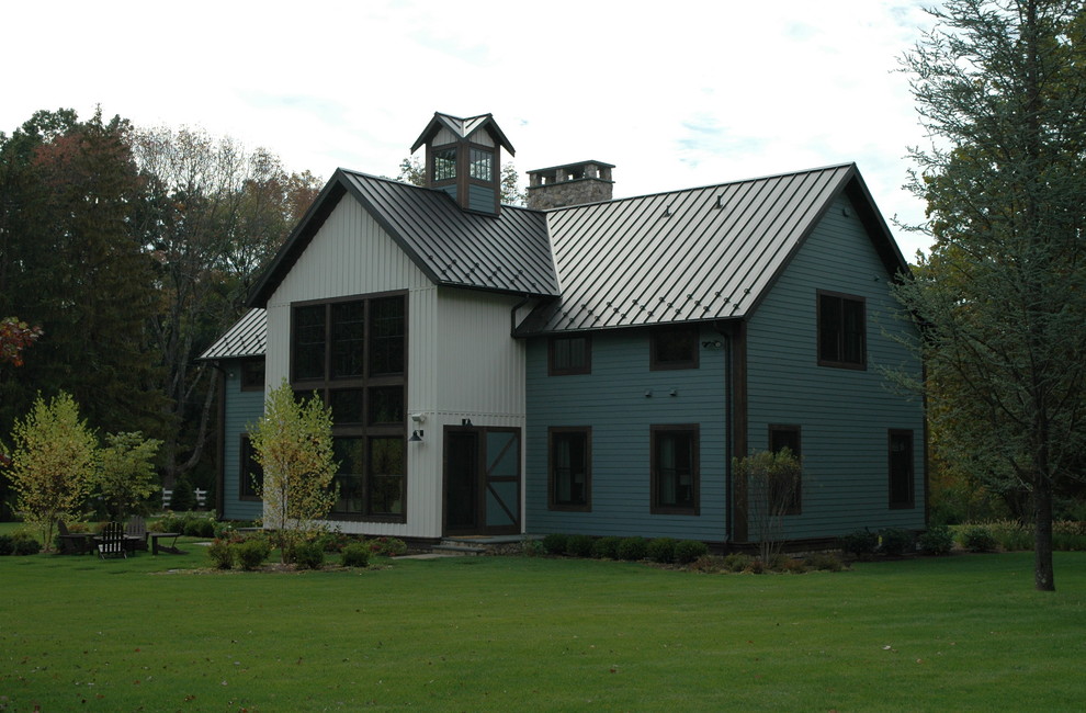Exemple d'une grande façade de maison bleue éclectique en bois à un étage avec un toit à deux pans et un toit en métal.