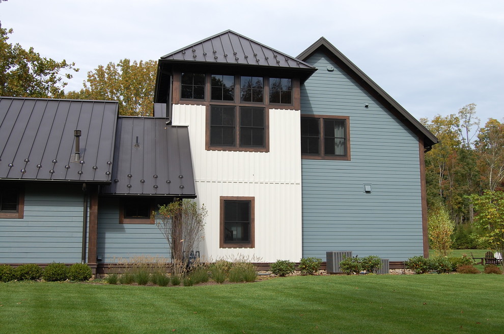 Стильный дизайн: большой, двухэтажный, деревянный, синий частный загородный дом в стиле фьюжн с двускатной крышей и металлической крышей - последний тренд