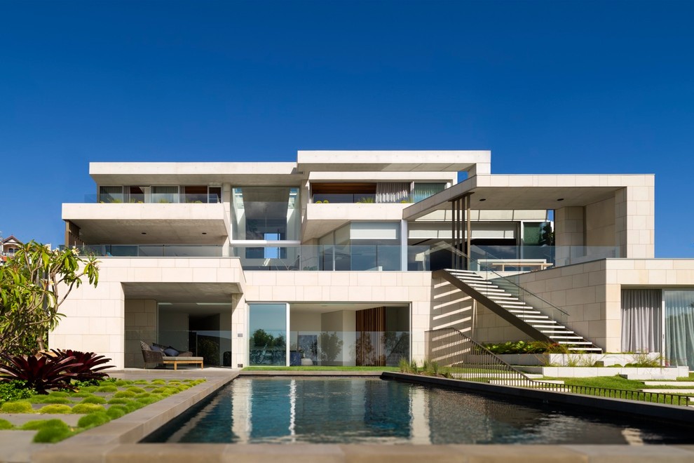 Immagine della villa beige contemporanea a tre piani con tetto piano