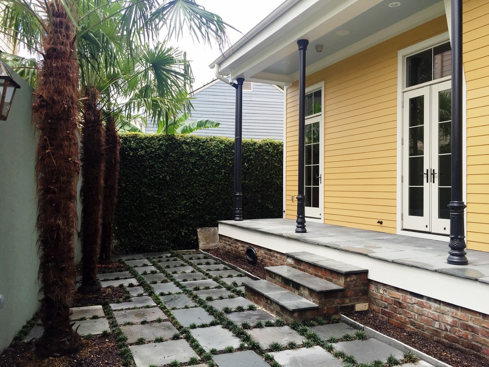 Kleines, Zweistöckiges Uriges Haus mit Vinylfassade, gelber Fassadenfarbe und Satteldach in New Orleans