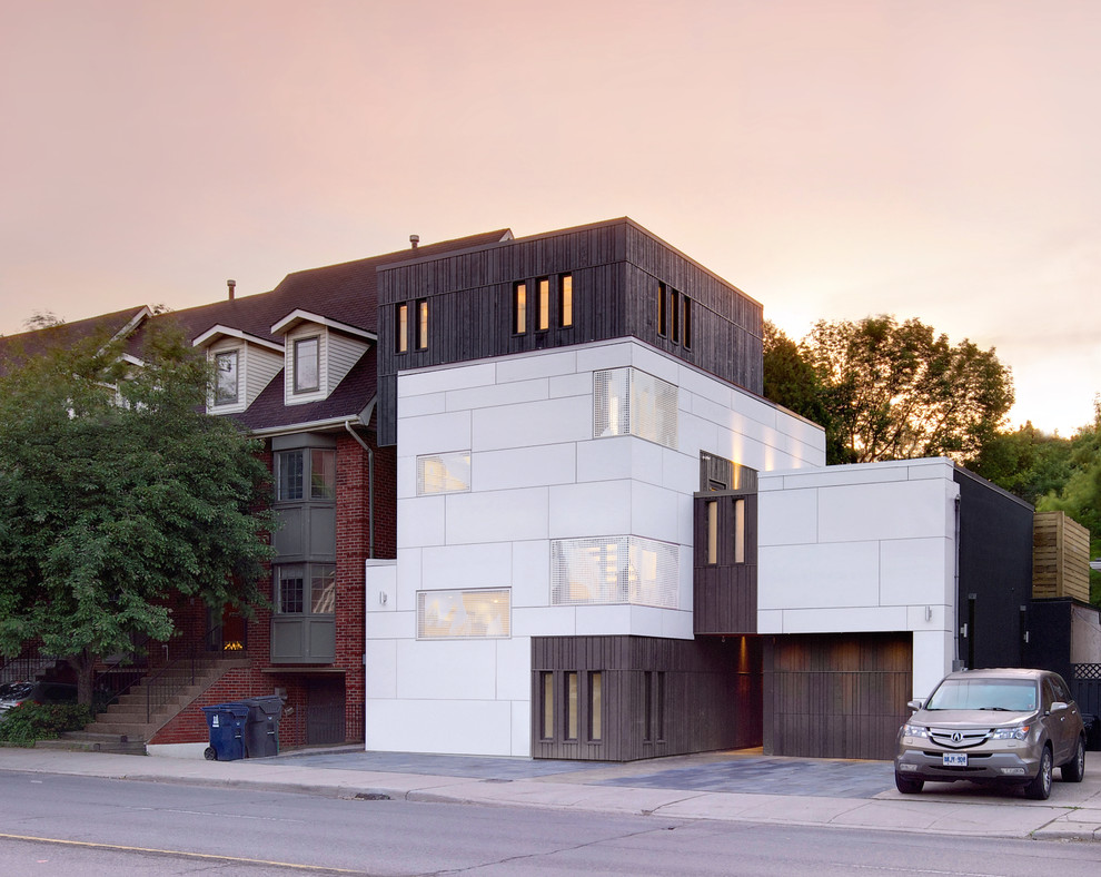 Large and white scandinavian house exterior in Toronto with three floors and concrete fibreboard cladding.