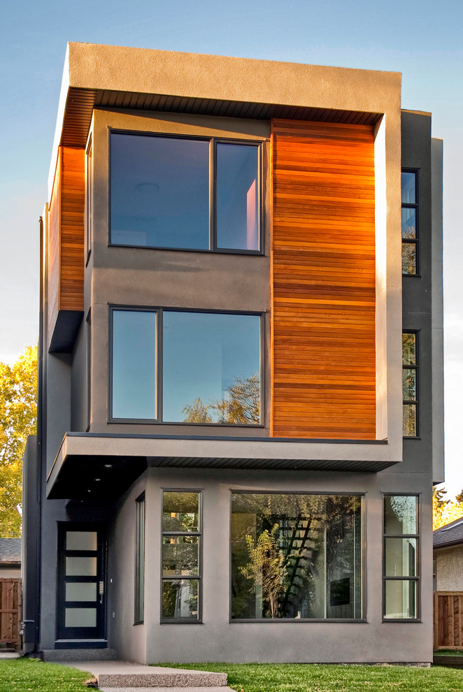 Diseño de fachada gris moderna de tamaño medio de tres plantas con revestimiento de madera y tejado plano
