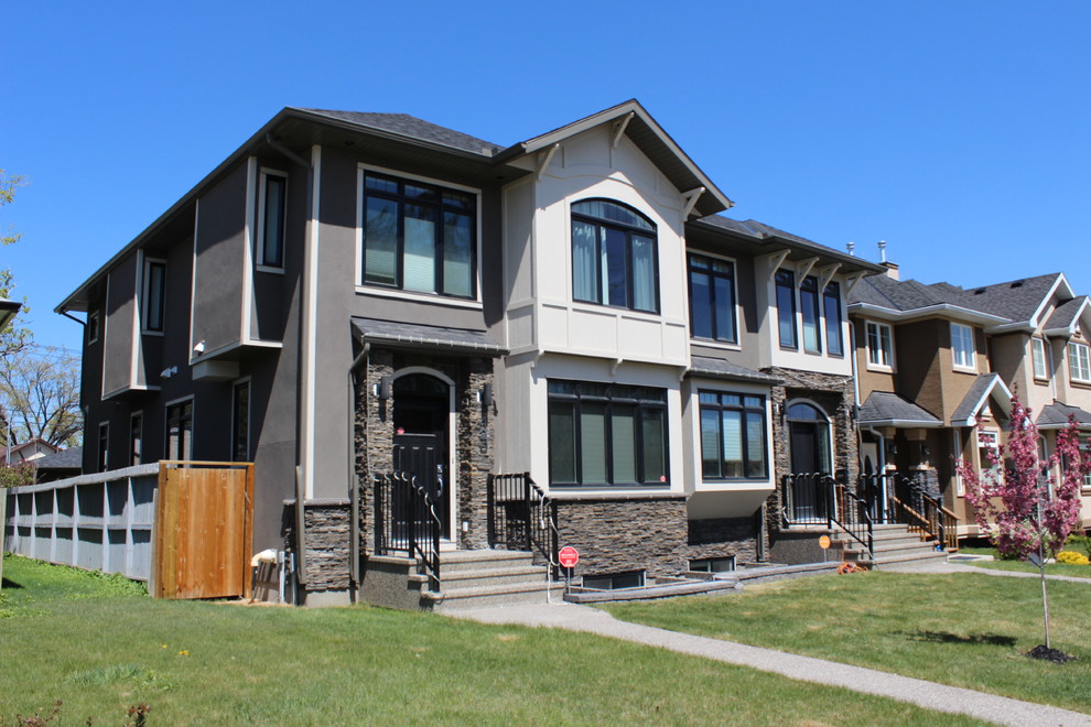 This is an example of a large and beige bohemian two floor house exterior in Calgary with stone cladding.