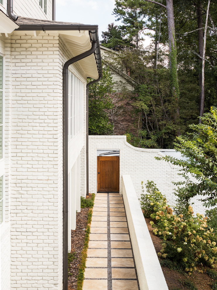 Foto della villa grande bianca contemporanea a tre piani con rivestimento in mattoni, tetto a capanna e copertura a scandole