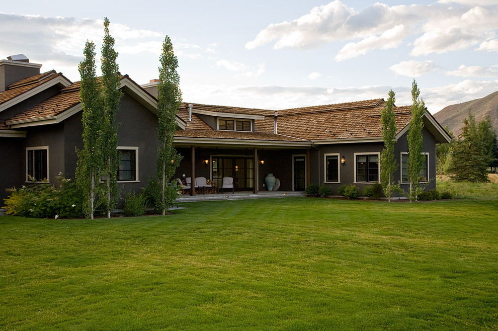 Aménagement d'une grande façade de maison verte classique en stuc à un étage avec un toit à croupette.